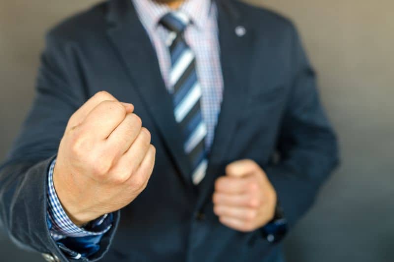 A man in a suit with fists signifying ready to fight